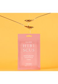 Pink packaging with white text labeled "HIBISCUS MOISTURIZING SCALP PACK w/ Honey," 50ml. Honey drips from metallic spoons against a yellow background.
