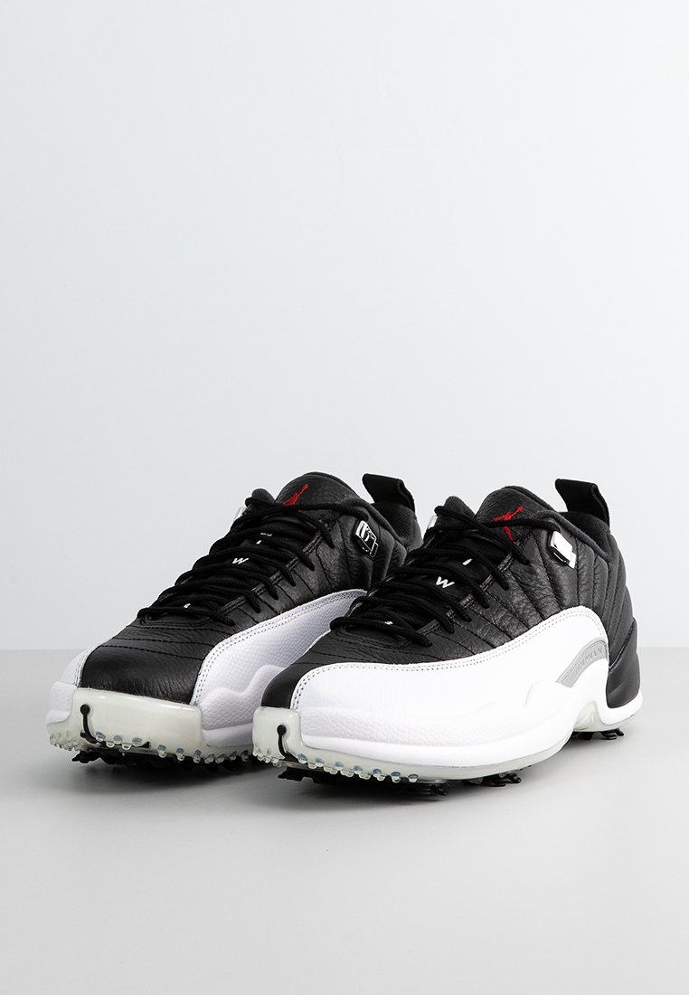 Czarno-białe sneakersy z skórzaną cholewką, strukturalnymi czarnymi panelami, białą podeszwą i gumowymi wypustkami dla lepszej przyczepności; posiadają czerwone akcenty.