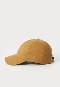 Casquette de baseball en coton marron avec un visière courbée, des détails cousus et une sangle réglable à l'arrière. Texture lisse et couronne arrondie.