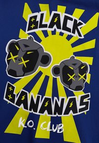 Blauwe T-shirt met afbeeldingen van twee aapgezichten in grijs, gele accenten en bold tekst met "BLACK BANANAS K.O. CLUB" tegen een gele explosie.