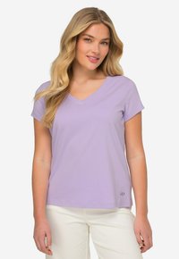 T-shirt pour femme à col en V et manches courtes en lavande. Fabriqué en tissu doux avec une texture lisse. Petit logo brodé en bas à gauche.