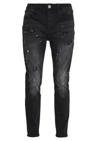 Black denim jeans featuring distressed details, scattered white paint splatters, and a slim-fit design with standard pockets and zip fly.
