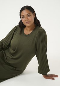 Robe verte olive avec une coupe décontractée ; présente des manches bouffantes gaufrées et un col rond ; texture de tissu lisse.