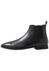 Svart läder Chelsea-boot med elastiska sidopaneler, spetsig tå och dragflik. Platt sula med en minimalistisk design och slät yta.
