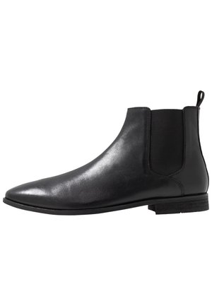 Schwarze Leder Chelsea-Boots mit elastischen Seiteneinsätzen, spitzer Zehenpartie und einer Ziehschlaufe. Flache Sohle mit minimalistischem Design und glatter Textur.