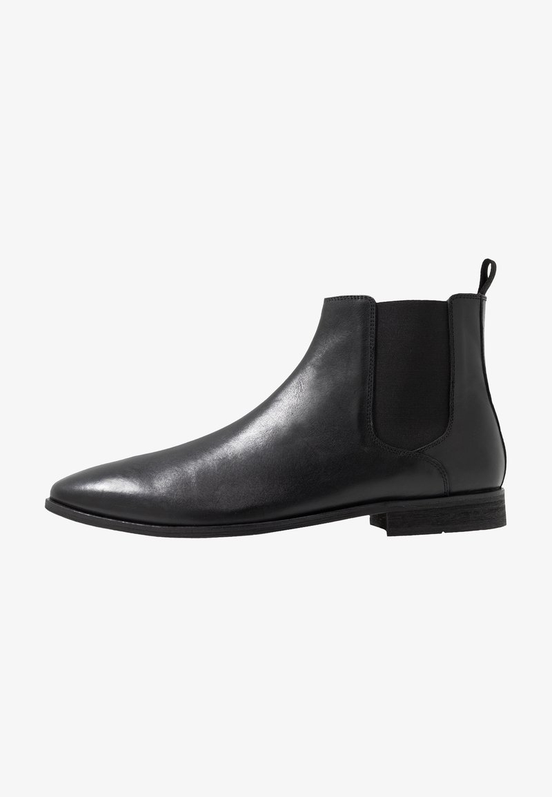 Svart läder Chelsea-boot med elastiska sidopaneler, spetsig tå och dragflik. Platt sula med en minimalistisk design och slät yta.