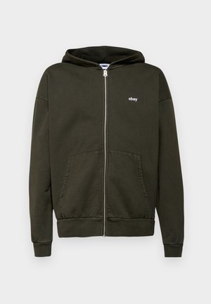 Dunkelolivgrüne Zip-Hoodie aus Baumwollmischung, mit zwei Vordertaschen, gerippten Bündchen und einem kleinen weißen Logo auf der Brust.