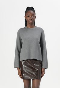 Grå genser med lange ermer og rund hals, parret med et brunt skinnskjørt med krokodillemønster, med en noe kort design.