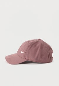 Μπεζ μωβ καπέλο μπέιζμπολ με καμπύλη γείσο και μικρό λευκό λογότυπο Nike στη μία πλευρά, παρουσιάζεται σε απλό λευκό φόντο.
