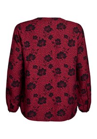 Blusa rossa con un motivo floreale nero e pois, con maniche lunghe e scollo rotondo, vista da dietro.