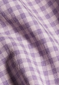 Tela de cuadros de color púrpura y blanco con una textura suave, que presenta un patrón clásico de cuadros en un estilo ligero y tejido.