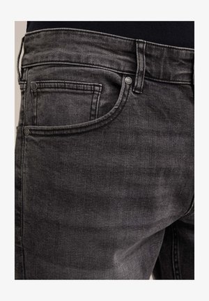 Črne jeans hlače iz denima z bledim videzom, ki imajo sprednji žep in kovinske gumbe za dekoracijo. Pas je enostaven brez dodatnih okraskov.