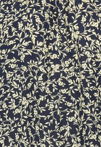 Tecido azul escuro com um padrão floral em creme, apresentando pequenas flores e folhas, dispostas em um delicado design por toda a superfície.