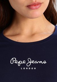 Marinblå t-shirt i mjukt, stretchy material med en vit logotyp "Pepe Jeans LONDON" över bröstet och rund halsringning.