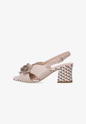 Beige faux leren slingback sandaal met een bloemaccent, open teen en een gepatternde blokhak met driehoeken in rood en zwart.