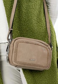 Borsa a tracolla in pelle beige con dettagli cuciti e catena argentata. La tracolla è nera e la borsa presenta un logo del brand.