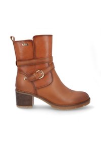 Bota de tobillo de cuero marrón con tacón apilado, correa decorativa y hebilla, y una pequeña etiqueta de "resistente al agua" cerca de la parte superior.