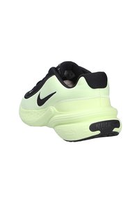 Zapatilla de running Nike en verde claro y negro, en ángulo para mostrar la parte trasera y lateral, con suela de espuma Phylon y logo Swoosh.