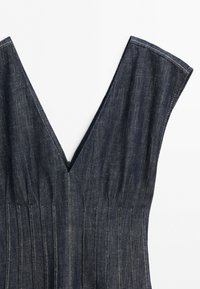 Robe sans manches en denim bleu foncé avec un décolleté en V profond et des détails de coutures verticales sur fond blanc.