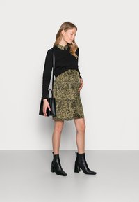 Camisola preta de mangas longas com uma saia verde de colarinho, adornada com um padrão de leopardo preto, combinada com botas de salto alto pretas até ao tornozelo e uma pequena bolsa.