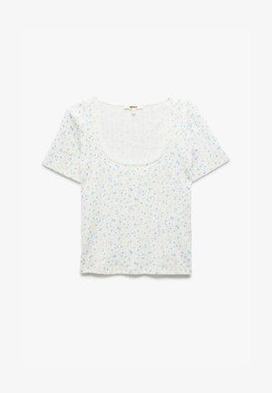 Koszulka krótko rękawowa w kwiatowy wzór z kwadratowym dekoltem. Wykonana z lekkiego materiału, z niebieskimi kwiatami na białym tle.