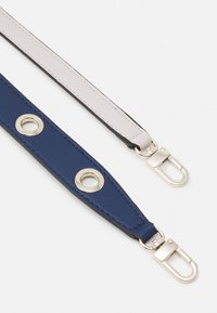 Leren band in marineblauw en lichtgrijs, met zilverkleurige hardware en oogjesdetails. Zachte textuur, platte uitvoering en clips aan de uiteinden.