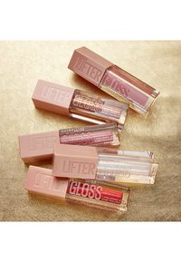 Vijf Lifter Gloss lipglossen in glanzende doorzichtige tubes met gestructureerde lichtbeige doppen, die tinten van nude, roze en rood tonen.