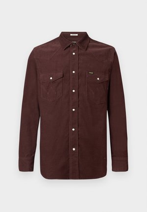 Langarm bruin corduroy shirt met drukknoopsluitingen, twee borstzakken met kleppen en een klein Wrangler-logo op de linkerzak.