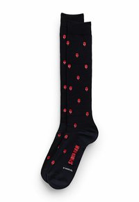 Svarta strumpor med mönster av röda Spider-Man-ansikten, med en ribbad kant och texten "SPIDER-MAN" i rött på sidan.