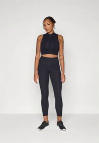 Juoda sportinė trumpa palaidinė su priekiu užtrauktuku, derinama su aukštakulnėmis juodomis kelnėmis. Abu turi lygų paviršių ir tamprų audinį. Juodi sportbačiai.