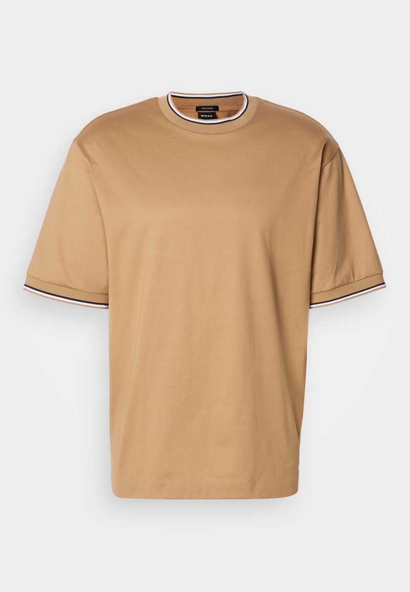 Camiseta de manga corta beige con borde a rayas en negro y blanco en el cuello y los puños, exhibida sobre un fondo blanco.