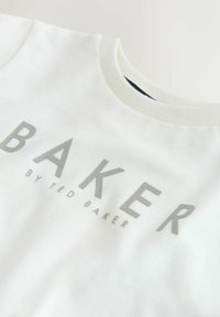 Biały T-shirt z krótkim rękawem wykonany z bawełny, z dużym srebrnym nadrukiem logo "BAKER" oraz mniejszym napisem "by TED BAKER".