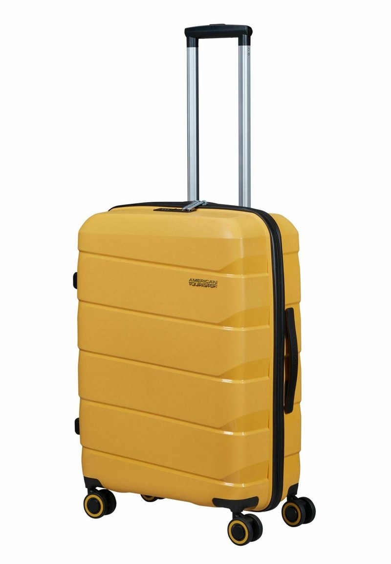 Geel harde koffer met gestructureerd oppervlak, zwarte rits, uitschuifbare handgreep en vier zwarte wielen met gele accenten.