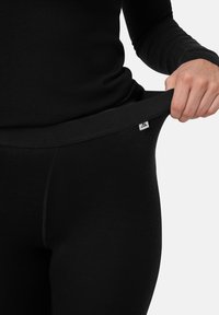 Leggings neri con una cintura elastica, texture liscia e un piccolo logo. Il tessuto appare leggero e aderente.