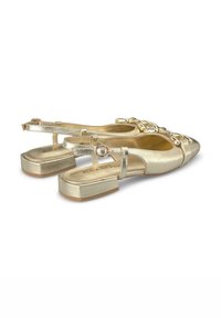 Zapatos slingback metálicos dorados con puntera afilada, tacón plano y detalle decorativo de cadena en el empeine. Textura suave y diseño minimalista.