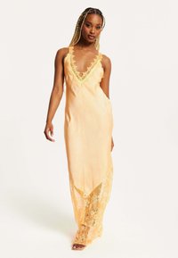 Long orange dress with lace trim, V-neckline, and sheer lace detailing at the hem. Smooth fabric with a flowy design.