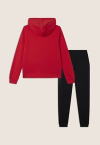 Felpa rossa con una texture morbida e cappuccio, abbinata a pantaloni sportivi neri. Entrambi hanno polsini elasticizzati e una vestibilità comoda.