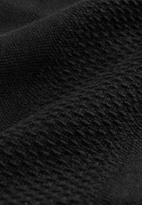 Tejido de punto negro que muestra un patrón texturizado con hilos entrelazados, con un aspecto suave y cálido.