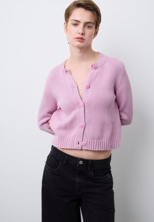 Light pink cropped knit cardigan with a round neckline, button closure, and ribbed hem. Features pink buttons and a textured surface.