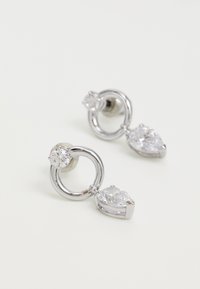 Uhani srebrne barve, ki imajo krožne in hruškaste oblike, okrašene s prozornimi dragulji, ki poudarjajo polirano teksturo in sodoben stil.