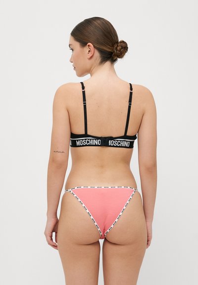 Soutien-gorge nero con spalline regolabili e una fascia con logo. Perizoma rosa con bordo bianco con logo. Tessuto liscio, design aderente, copertura minimale.