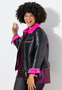 Zwarte leren jas met een felroze faux fur kraag en manchetten. Beschikt over een ritssluiting, voorzakken en contrasterende roze stiksels.