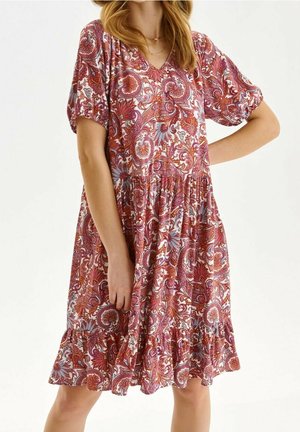 Donna che indossa un vestito al ginocchio con motivo paisley rosso, arancione e viola, maniche corte a sbuffo e scollatura a V.