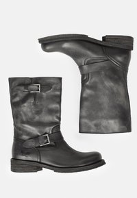 Botas de tobillo de cuero negro con punta redonda, tacón bajo en bloque, correa decorativa con hebilla y acabado texturizado. Construcción duradera con detalles de costura.