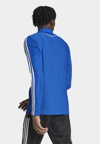 Blue sports jersey made of textured mesh fabric. Features white striped accents along the sleeves, with a collar design.