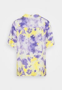 Camicetta a maniche corte con motivo tie-dye in viola e giallo. Realizzata in tessuto leggero con una vestibilità rilassata e dettaglio sulla tasca posteriore.