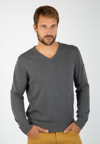 Grå v-hals sweater i blødt strikkemateriale med ribbet manchetter og kant. Har en klassisk pasform og minimal brandingdetalje på ærmet.