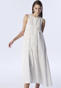 Vestido blanco sin mangas con detalles fruncidos y acentos de cordón a lo largo de los lados; silueta fluida hasta la rodilla, hecho de un tejido ligero.