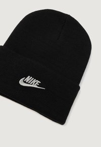 Černá pletená čepice s ohrnutým lemem, na přední straně s vyšitým šedým logem Nike. Měkká textura a těsné padnutí.