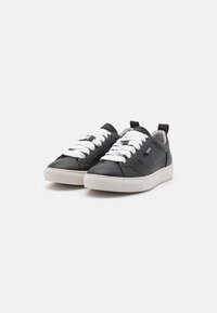 Sneaker in pelle nera con lacci bianchi, superficie testurizzata, punta rotonda e suola in gomma bianca a contrasto. Presenta un pratico tassello sul retro.